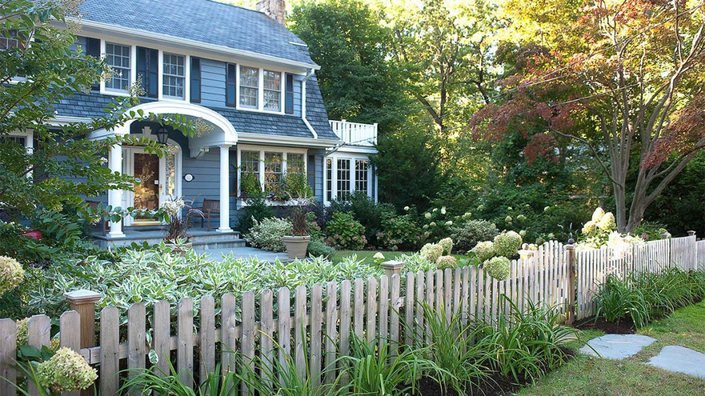 Front yard landscape of a home with a picket fence and different plants like Limelight hydrangeas and Ivory Halo dogwood.