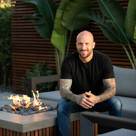 designer mike pyle sitting next to a fire pit